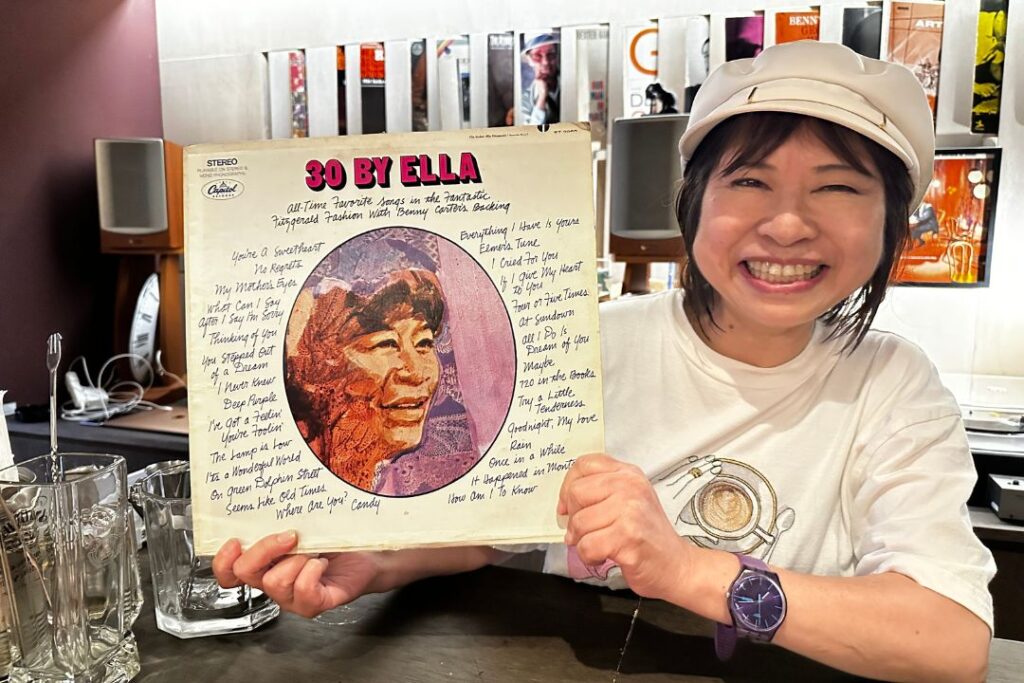 ジャズのレコードを持って笑顔でほほ笑むオーナー